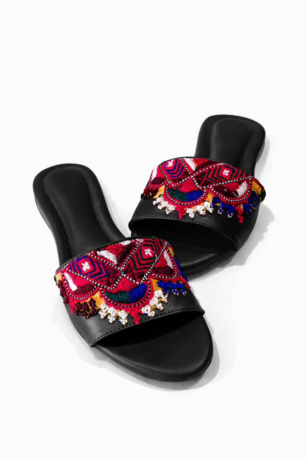 Black slides with colorful patterned straps on a white background