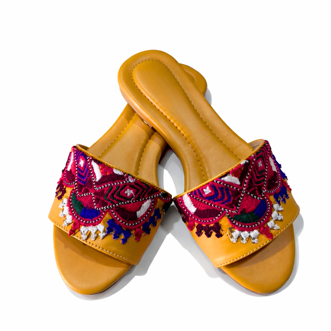 Pair of yellow sandals with colorful embroidery on a white background