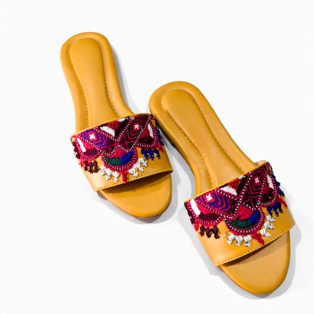 Pair of yellow sandals with colorful embroidered straps on a white background