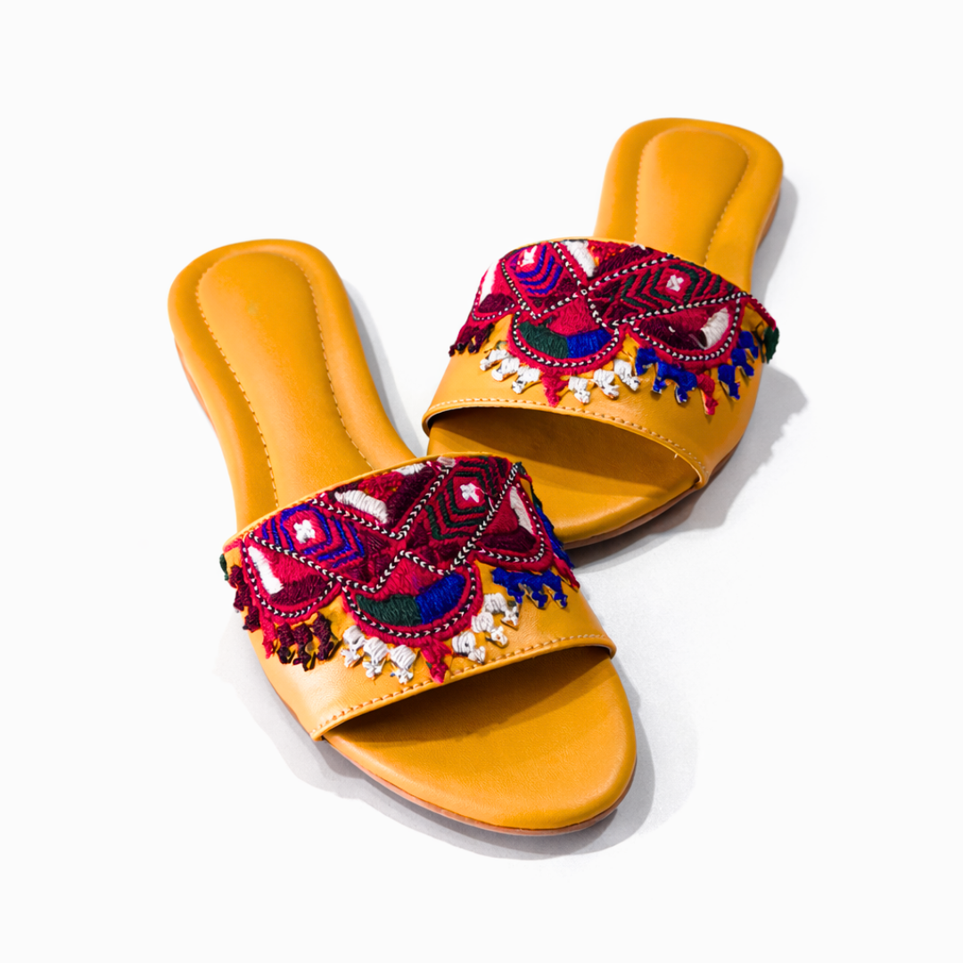 Pair of orange sandals with colorful embroidery on a white background