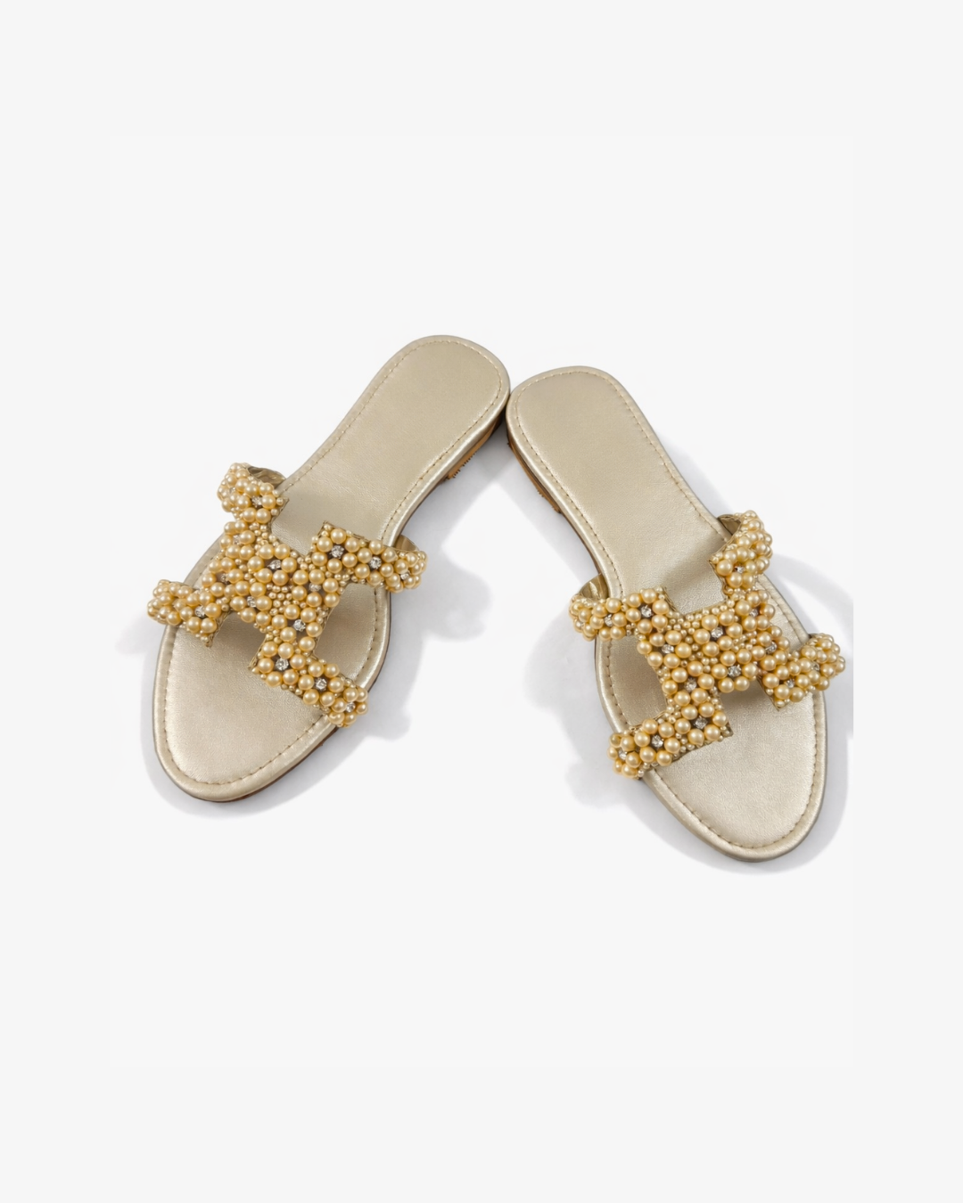 Pair of gold embellished sandals on a white background