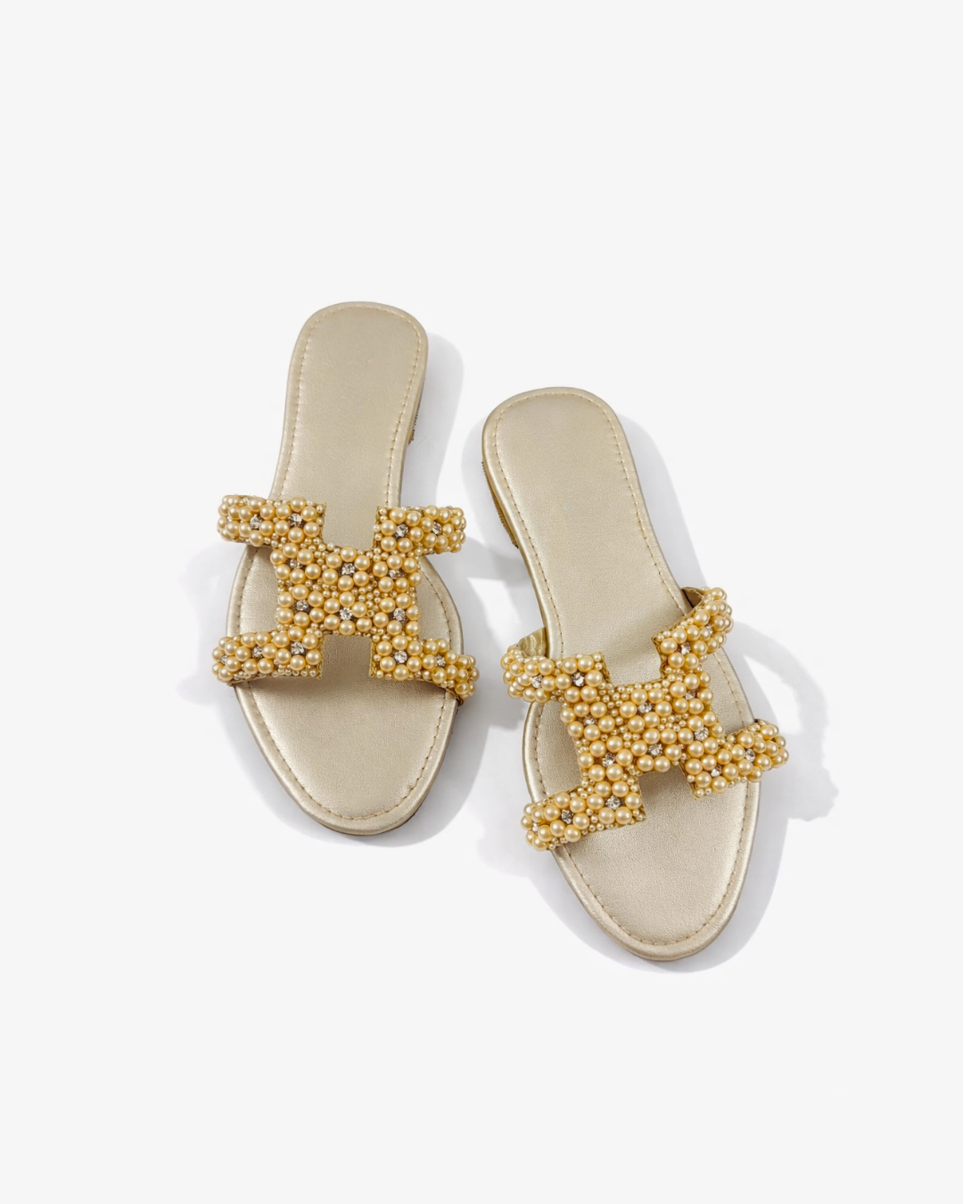 Gold embellished sandals on a white background